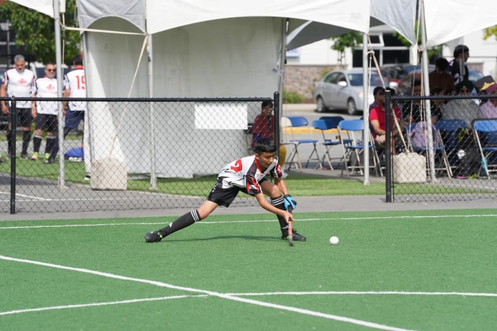 Player stretching low with stick on turf